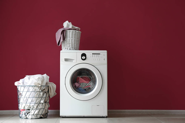 Machine à laver moderne et buanderie près du mur de couleur
 - Photo, image