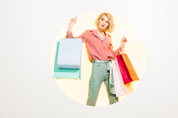 beautiful stylish girl posing with shopping bags on white with yellow circle - Φωτογραφία, εικόνα