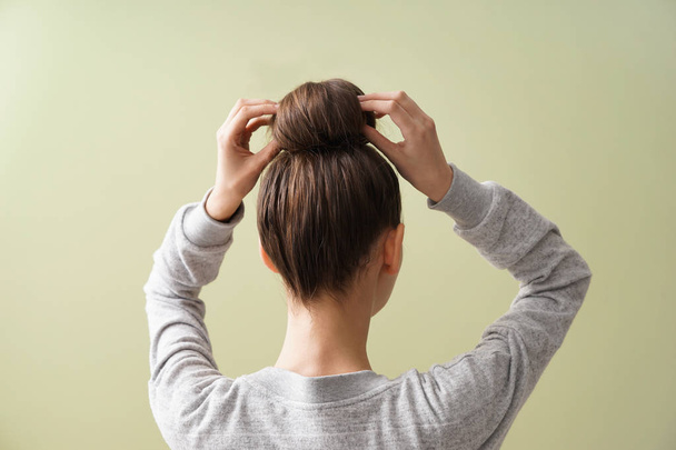 Young woman with hair bun on color background - Foto, imagen