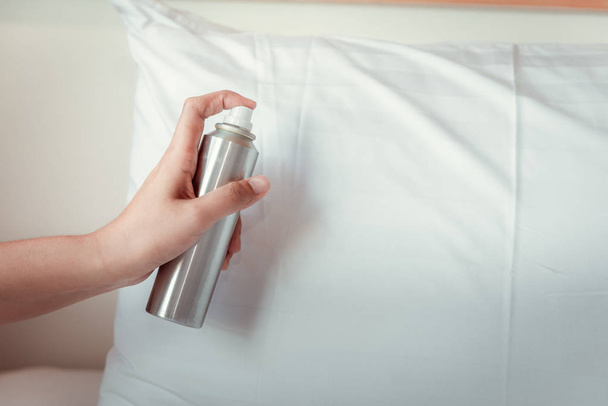 Femme main est pulvérisation désodorisant dans l'oreiller sur la chambre à coucher
 - Photo, image
