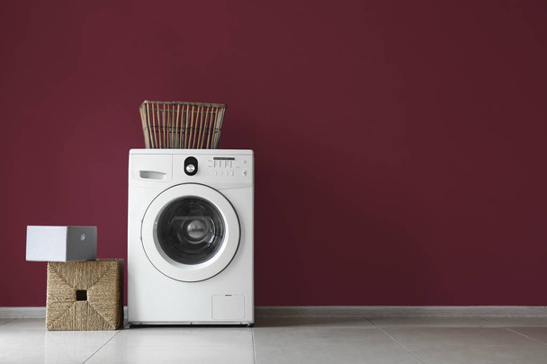 Modern washing machine and laundry near color wall - Φωτογραφία, εικόνα