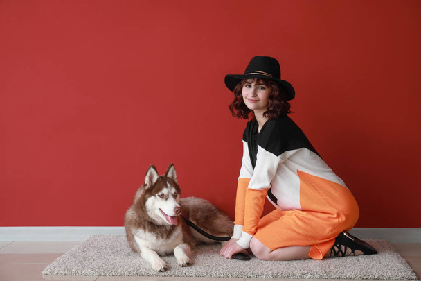 Mujer joven con su lindo perro cerca de la pared de color
 - Foto, imagen