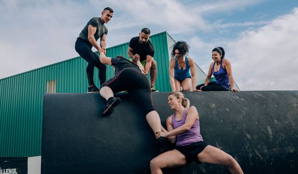 Participants à un parcours d'obstacles grimpant un tambour
 - Photo, image