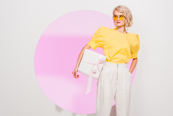 beautiful fashionable girl holding gift box on white with pink circle - 写真・画像