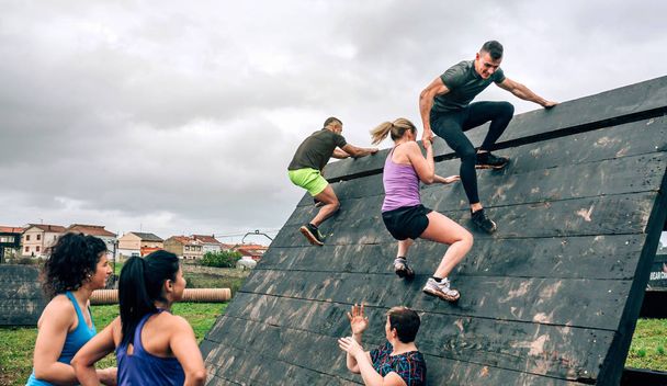 Participantes no obstáculo da pirâmide de escalada do curso de obstáculo
 - Foto, Imagem