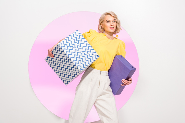 beautiful stylish girl holding gift boxes on white with pink circle - 写真・画像