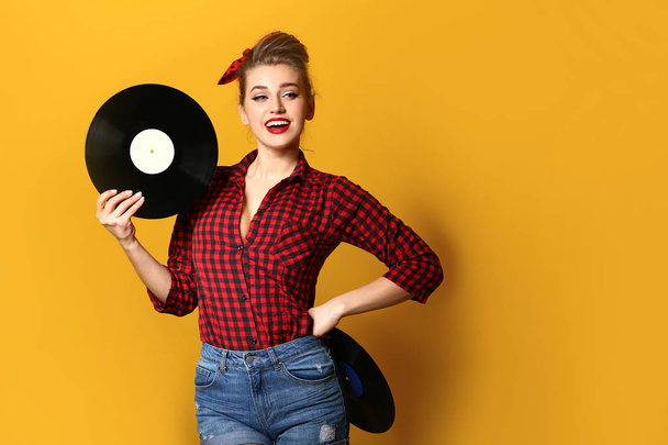 Beautiful pin-up woman with vinyl discs on color background - Photo, image