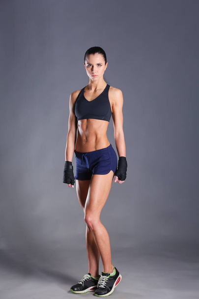 Muscular young woman posing in sportswear against black background - Zdjęcie, obraz