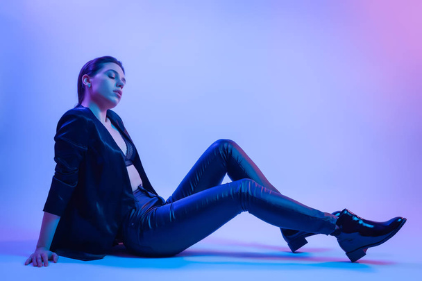 Cinematic night portrait of woman in  neon. High Fashion model girl in a stylish clothes  in colorful bright neon lights posing in studio, portrait of beautiful woman in   t-shirt and trousers.  - Fotografie, Obrázek