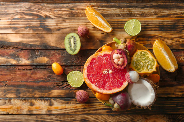 Ahşap masa üzerinde lezzetli egzotik meyve ürün yelpazesine plaka - Fotoğraf, Görsel