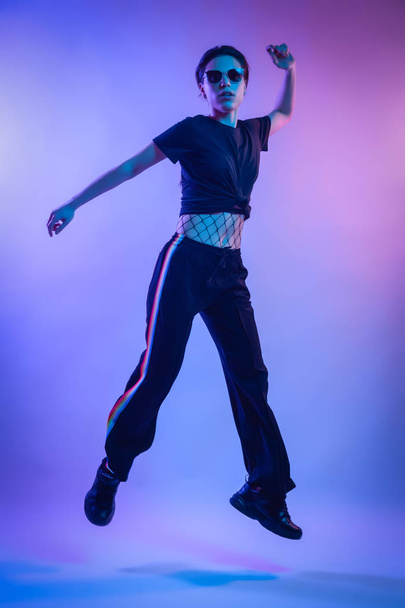 High Fashion model  woman in fashion t-shirts and pants with stripes in colors lgbt in colorful bright neon uv blue and pink lights, posing in studio. Fashion concept and Zine culture - Φωτογραφία, εικόνα