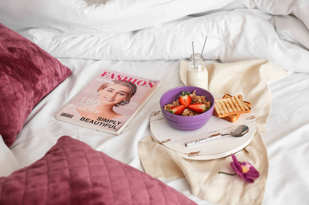 Tray with healthy breakfast and magazine on bed - Φωτογραφία, εικόνα
