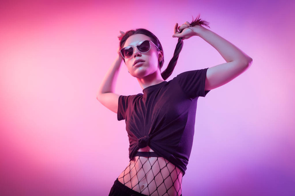 High Fashion model  woman in fashion t-shirts and pants with stripes in colors lgbt in colorful bright neon uv blue and pink lights, posing in studio. Fashion concept and Zine culture - Фото, изображение