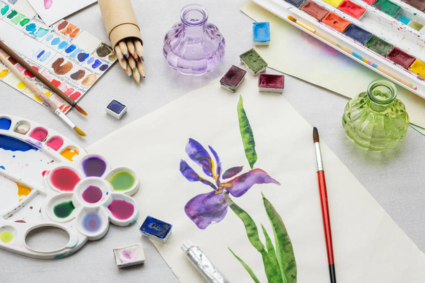 Watercolor drawing - Iris flower - and artistic equipment on desk. Top view. - Photo, image