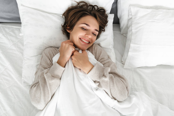Smiling young girl relaxing in bed - Valokuva, kuva