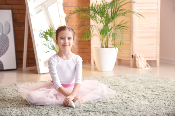 Aranyos kis balerina otthon a szőnyegen ülve - Fotó, kép