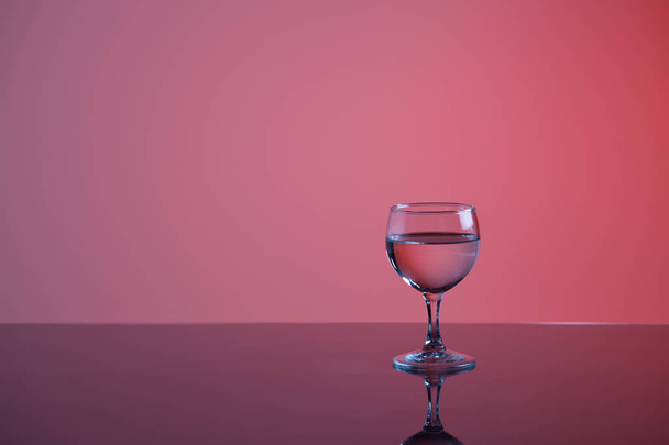close-up view of glass with transparent liquid on purple background - Zdjęcie, obraz