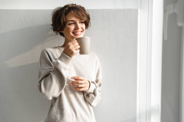 Uśmiechnięta młoda kobieta o filiżance herbaty - Zdjęcie, obraz