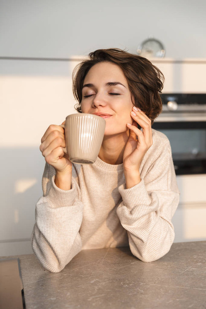 Smiling young woman having cup of tea - Fotoğraf, Görsel