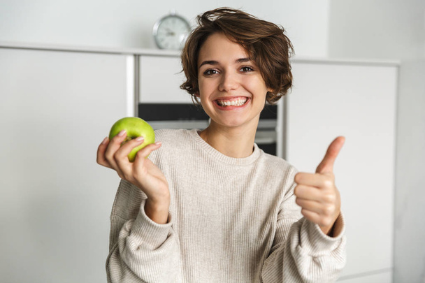 Smiling young woman holding green apple - Φωτογραφία, εικόνα