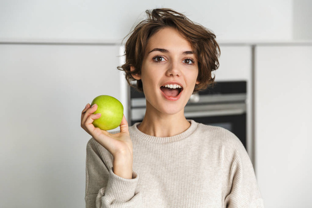 Smiling young woman holding green apple - Фото, зображення