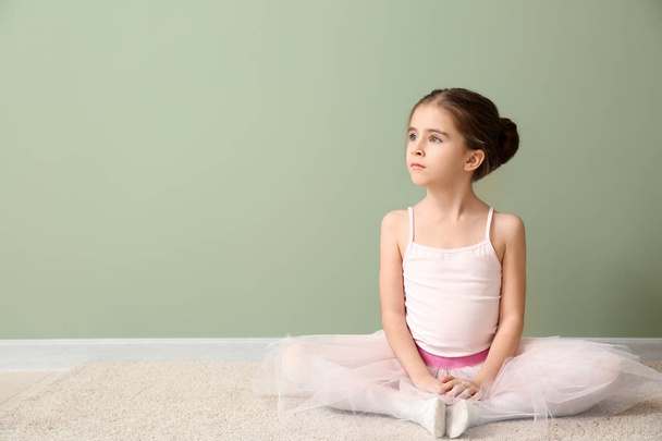 Cute little ballerina sitting near color wall - Fotó, kép