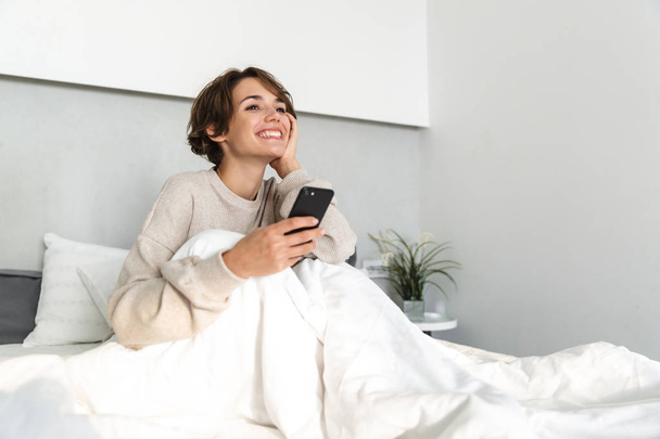 Smiling young girl relaxing in bed - Foto, Bild