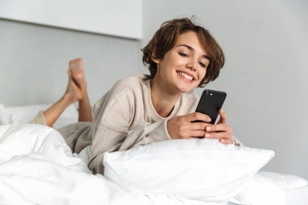Smiling young girl relaxing in bed - Fotó, kép
