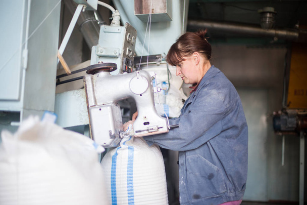 14 october 2014.Ukraine.Kyiv.Work on the production of agricultural products. A Caucasian woman dressed in an iniform performs work on a conveyor that packs bulk products into large bags. - Fotó, kép