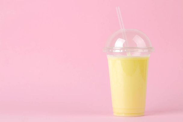 Making a milkshake. plastic disposable glass with a banana milkshake on a bright trendy pink background. space for text - 写真・画像