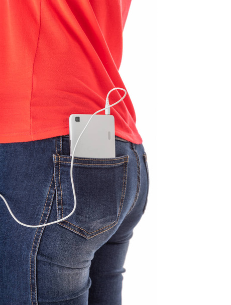 Girl in jeans and a red T-shirt with a smartphone with white headphones. - Foto, Imagem