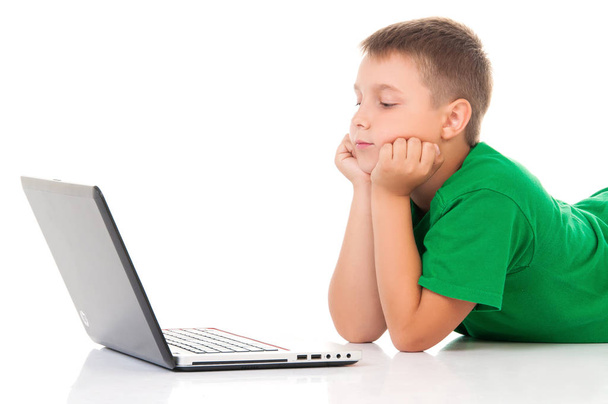 casual teenager in bright green t-shirt with laptop over white background. Use or harm of computer games, children's leisure and schooling - Fotografie, Obrázek