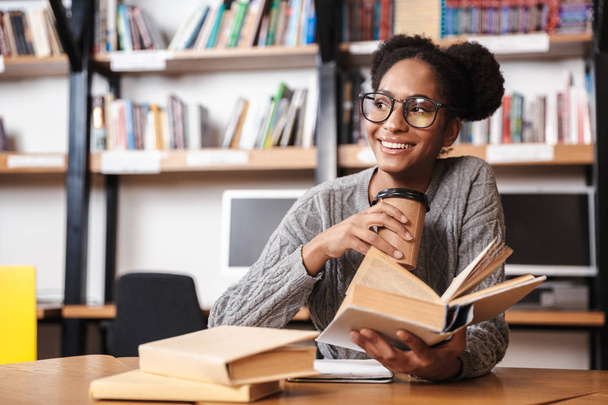 Щаслива молода студентка, яка навчається в бібліотеці
 - Фото, зображення