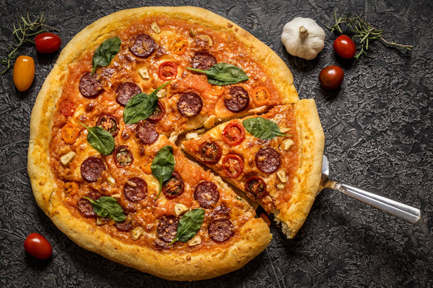 pizza with salami sausage, spinach and cherry tomatoes and tomato sauce on a dark background - Φωτογραφία, εικόνα