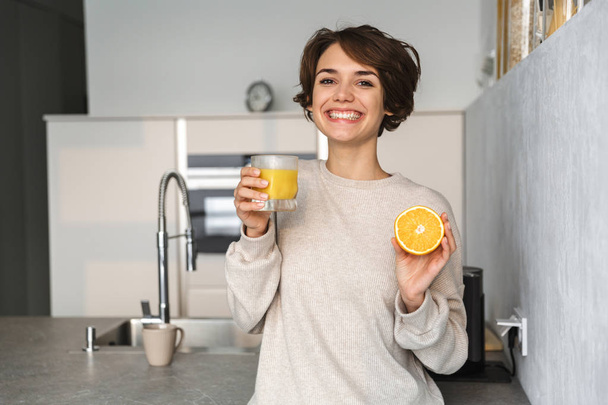 Smiling young woman holding orange - Foto, afbeelding