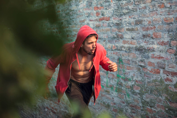 Determined young man in a red hooded shirt preparing for workout - Photo, Image