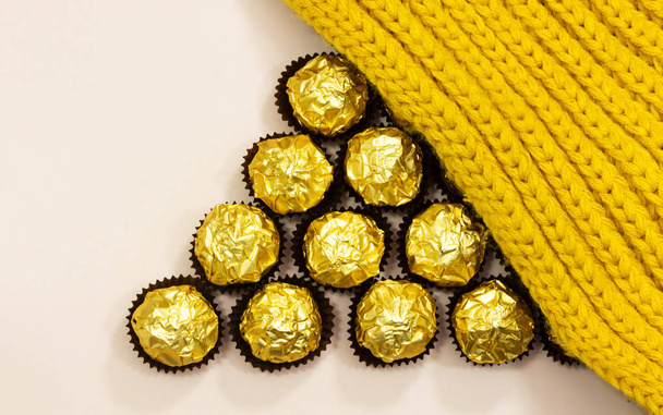tvoří trojúhelník tvar od zlaté prémiové čokoládové sladkosti pod vlněné zimní šála - Fotografie, Obrázek