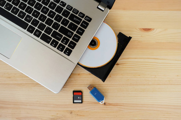 SD Card, Flash Drive USB3.0 и CD DVD Drive Writer Burner Reader ноутбука компьютера на деревянном фоне, Концепция хранения данных устройства
 - Фото, изображение