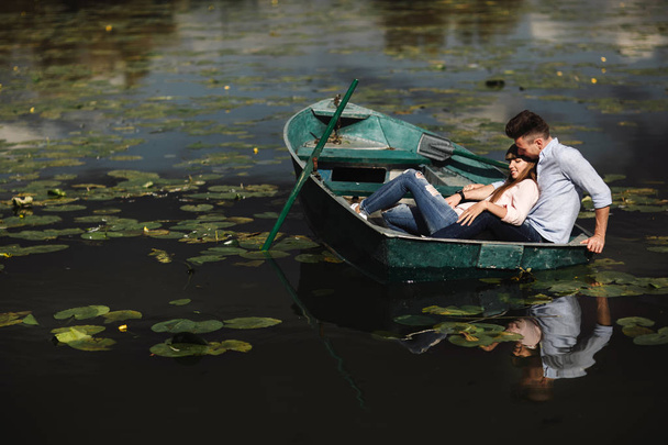 Gewoon ontspannen. Mooie jonge paar genieten van romantische datum terwijl roeien een boot. Verliefde paar rustend op een meer tijdens het rijden van een groene boot. romantiek. - Foto, afbeelding