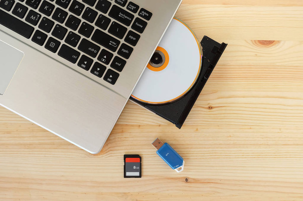 SD kaartlezer, Flash Drive Usb3.0 en Cd Dvd Drive schrijver brander van laptop op houten achtergrond, Concept van apparaat voor gegevensopslag - Foto, afbeelding