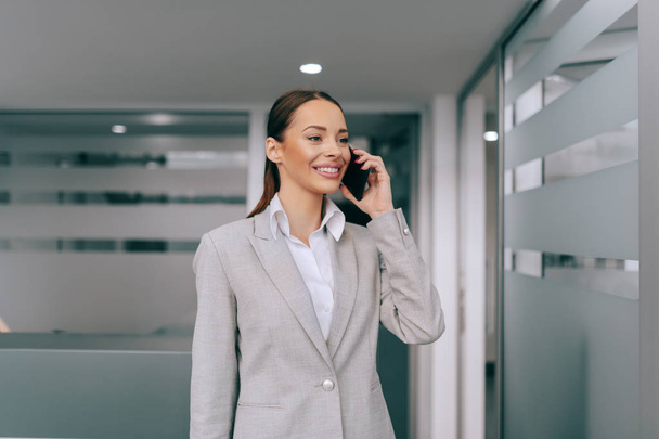Красивая белая деловая женщина, стоящая в офисе со смартфоном для делового звонка. Трудно победить человека, который никогда не сдаётся.
. - Фото, изображение