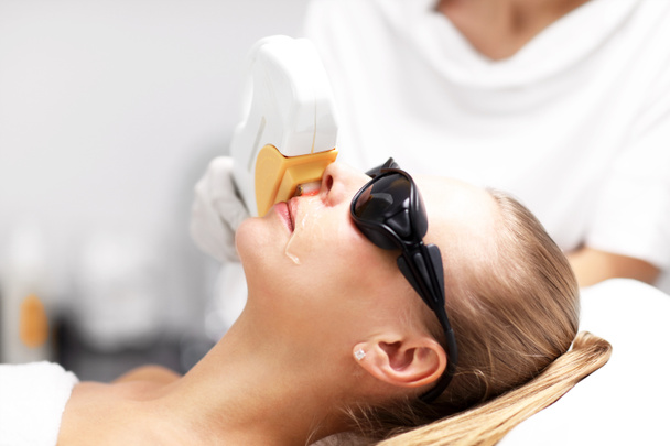 Estetista dando trattamento laser di epilazione alla donna sul viso
 - Foto, immagini