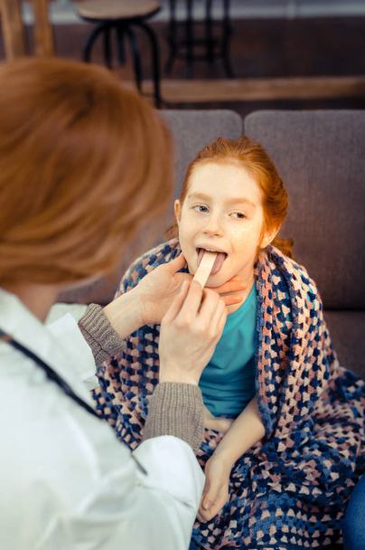 Pleasant red haired girl having her throat examined - Fotoğraf, Görsel