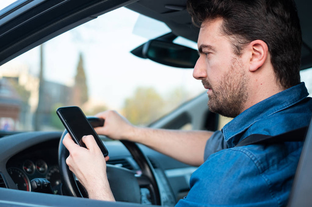 Αρσενικό σε αυτοκίνητο χρησιμοποιεί κινητό τηλέφωνο στο τιμόνι - Φωτογραφία, εικόνα