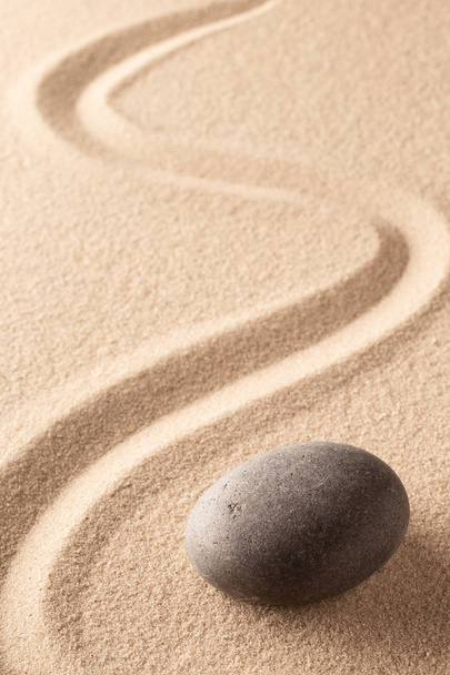 curved line in the sand of a zen stone garden. A round black rock on sandy background. Concept for spirituality, harmony and balance.  - Φωτογραφία, εικόνα