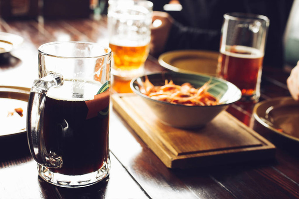vrienden drinken bier uit mokken in brouwerij pub - Foto, afbeelding