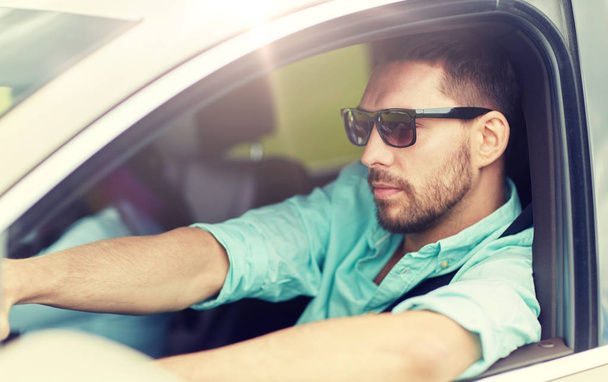 young man in sunglasses driving car - Foto, afbeelding