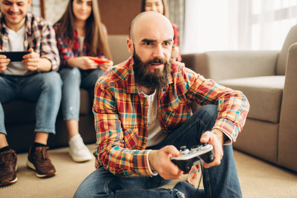 Mosolyogva meg a joystick játszik otthon a tv konzol. A játékosok játszani a videojáték, a férfi és a női játékosok Gamepad joypads csoport - Fotó, kép
