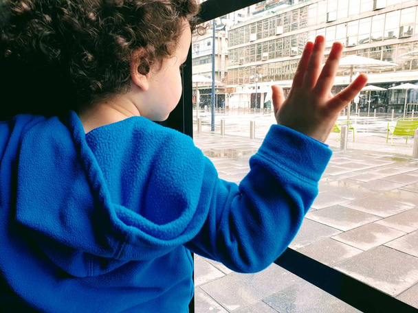 Le petit garçon pose ses mains sur une fenêtre
 - Photo, image