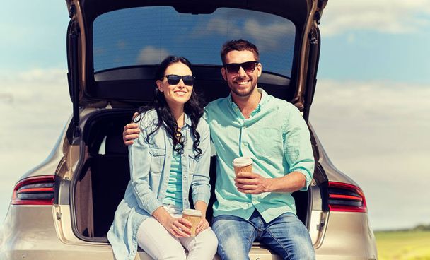 happy couple with coffee at hatchback car trunk - Фото, изображение